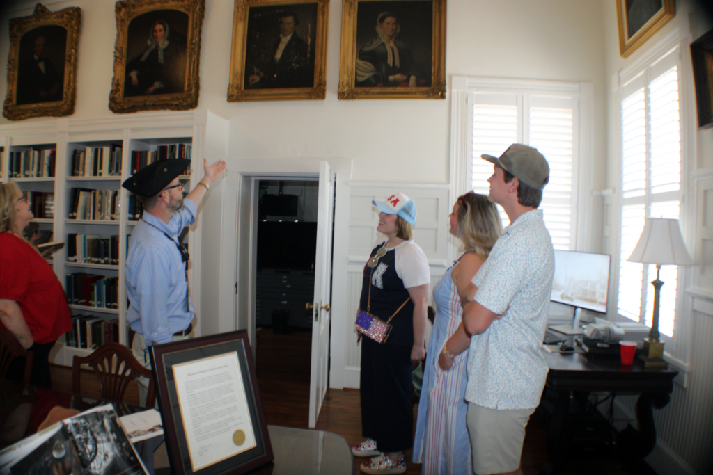 people looking up at four portraits of people with one person pointing