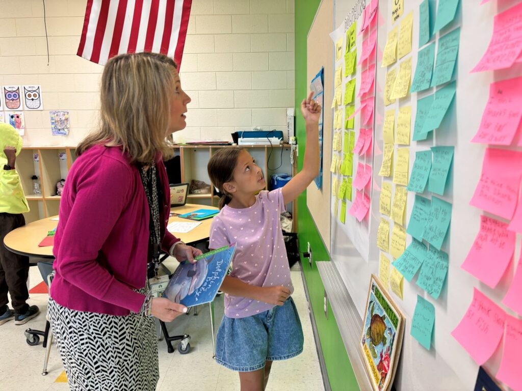 Second grader points to KWL chart showing adult