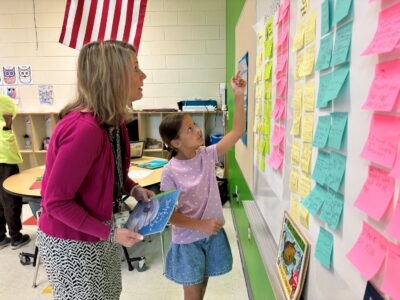 Second grader points to KWL chart showing adult