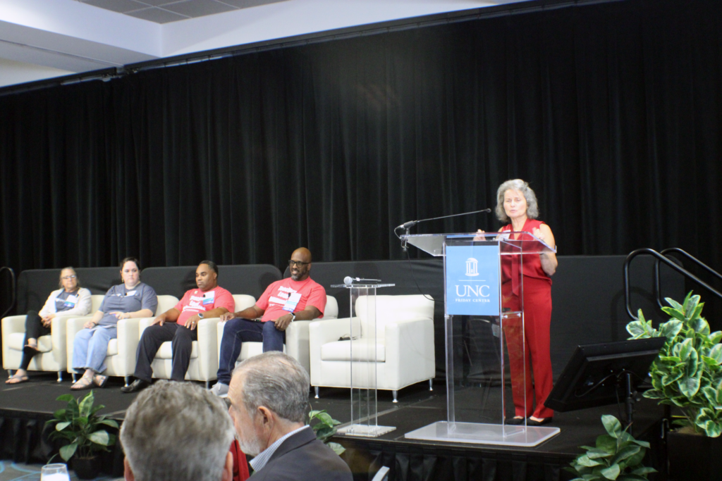 people sitting on stage one woman at podium