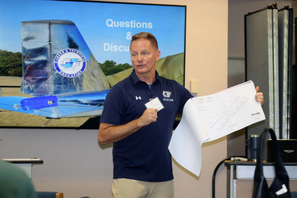 man standing in front of a power point holding and 11x7 paper